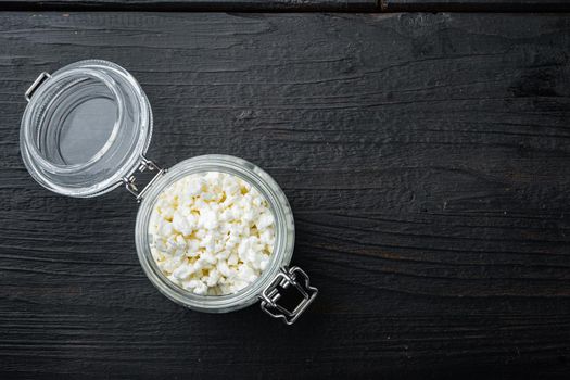 Cottage cheese, curd, on black wooden table, top view with space for text
