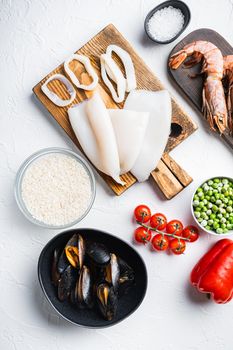 Raw ingredients for paella with seafood on white background, top view, food photo.