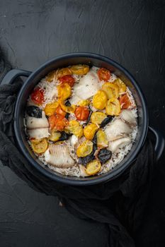 White tilapia fish, with basmati rice and cherry tomatoes, on black background, top view