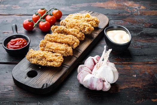 Breaded chicken wings cuts on dark wooden background.
