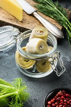 Pickled artichokes with oil, on grey background