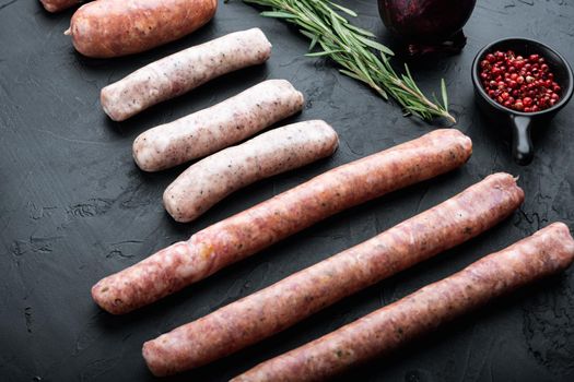 Raw sausages set, on black background.