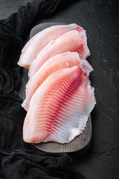 White tilapia fish fillet cuts on black background