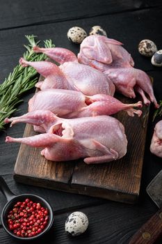 Fresh raw meat quails with herb, on black wooden background