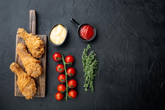 Fried crispy chicken legs, drumstick parts on black background, flat lay, with copy space.