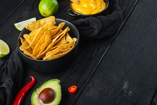 Corn tortilla chips nachos and dip sauce, on black wooden background with copy space for text