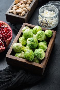 Brussels sprouts with pomegranate, cottage cheese and pistachios, on black textured background