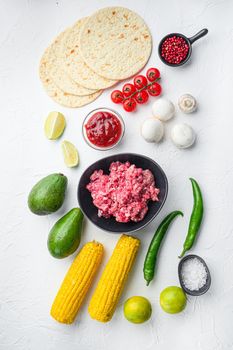 Ingredients for tacos with minced beef meat, corn tortillas, chili, avocado, over white background. Top view