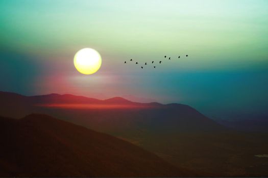 sunrise on morning sky over green mountain and silhouette bird flying on rainbow sky in Lopburi Thailand