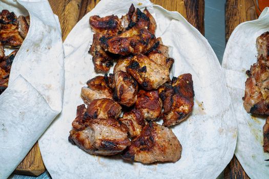 Shish kebab in pita is ready to eat. Lavash with barbecue on a wooden board.