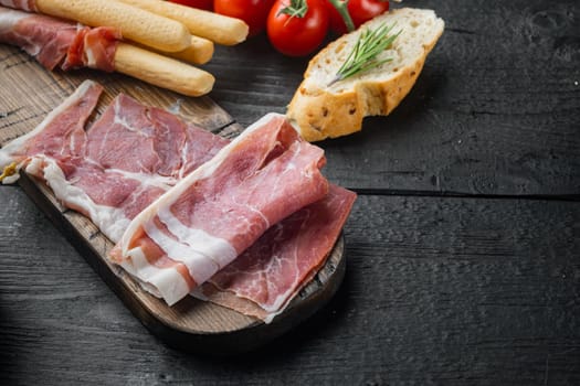 Pile of tasty hamon set, on black wooden table with copy space for text