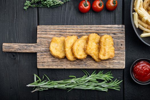 Homemade chicken nuggets fried on black wooden table, top view.