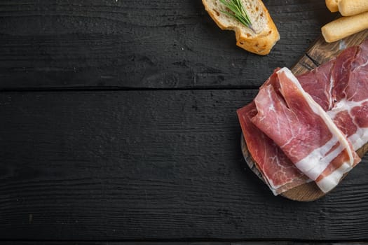 Sliced jamon set, on black wooden table, flat lay with copy space for text