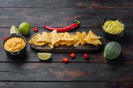 Mexican crispy snack, nachos chips and cheese guacamole avocado sauces, on old wooden table