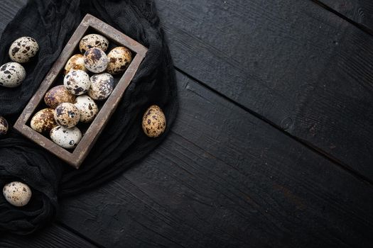 Fresh quails eggs, flat lay, on black wooden background with space for text