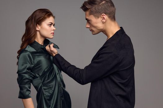 A woman in a silk dress and an aggressive man in a suit on a gray background look at each other. High quality photo