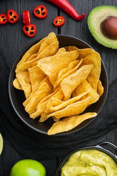 Nachos corn chips with traditional dip sauce set, on black wooden background, top view or flat lay