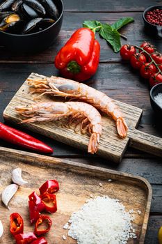 Traditional paella valenciana raw ingredients with shrimps, mussel, rice and squid over dark rustic wooden background, food photo.