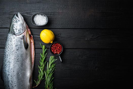 Fresh rainbow trout on black wooden surface, flat lay with copy space.