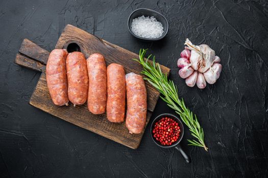 Raw organic pork sausages, top view, on black background.