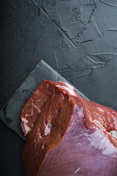 Raw liver on black background, flat lay with copy space.