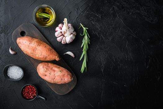 Sweet potato or batat with herbs and spices on black background, top view with space for text.