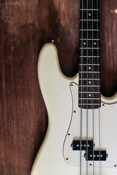 white electric bass guitar on wood background with copy space