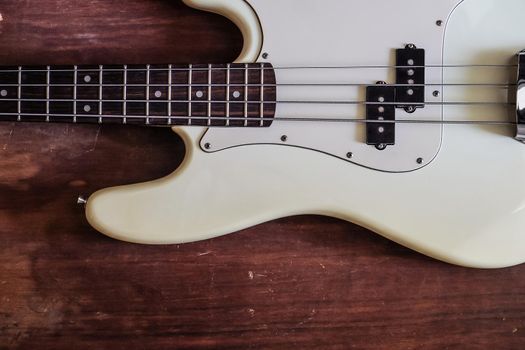 white electric bass guitar on wood background with copy space