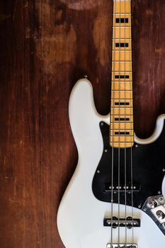 white electric bass guitar on wood background with copy space