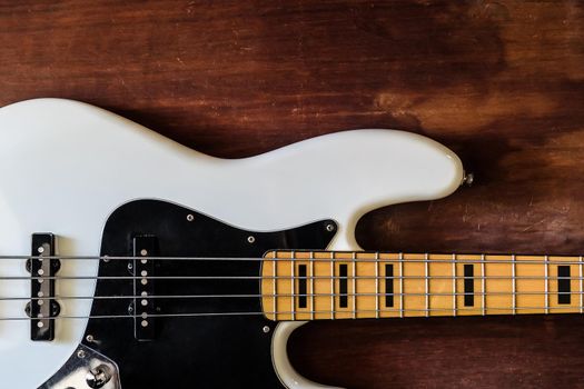 white electric bass guitar on wood background with copy space