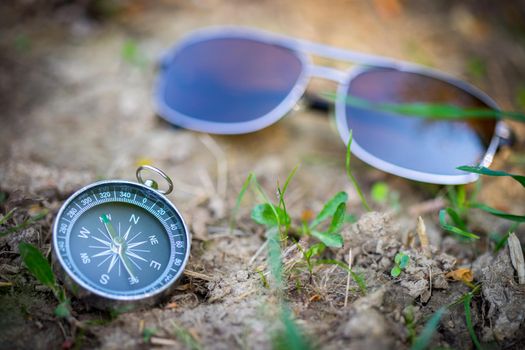 Vintage compass and sunglasses lying on the floor. Adventure and discovery concept.