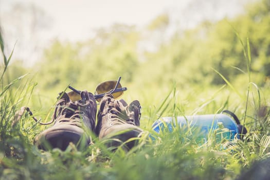 Shoes and a bottle of water in the green grass. Free time in summer.