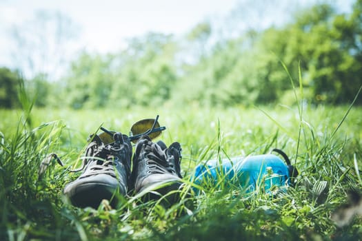 Shoes and a bottle of water in the green grass. Free time in summer.