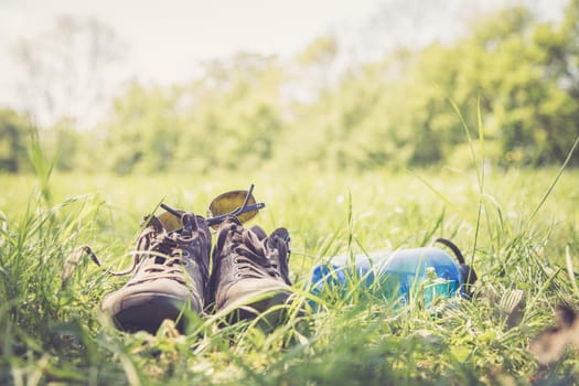 Shoes and a bottle of water in the green grass. Free time in summer.