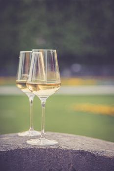 Glass of white wine on a stone wall in the formal garden. Enjoying it in the own garden in the evening sun.