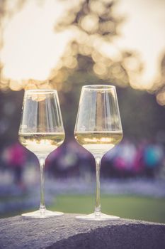 Glass of white wine on a stone wall in the formal garden. Enjoying it in the own garden in the evening sun.