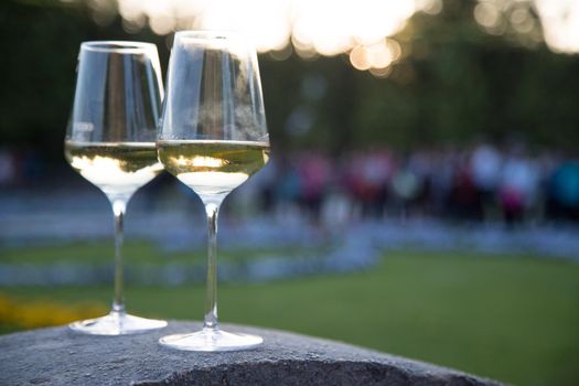 Glass of white wine on a stone wall in the formal garden. Enjoying it in the own garden in the evening sun.