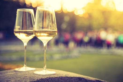 Glass of white wine on a stone wall in the formal garden. Enjoying it in the own garden in the evening sun.
