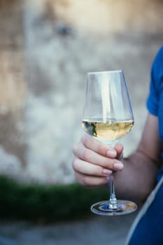 Glass of white wine on a stone wall in the formal garden. Enjoying it in the own garden in the evening sun.