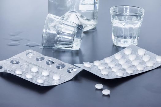 Pills and alcohol on a grey table. Concept for drug abuse.