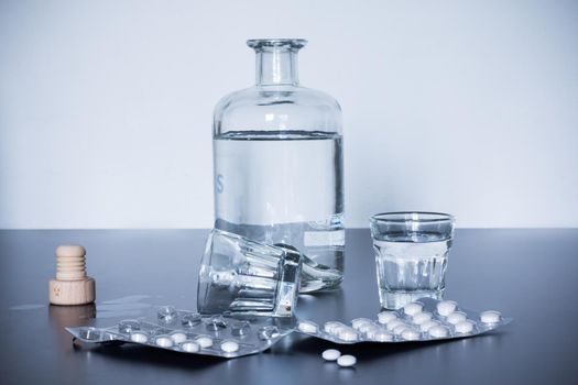 Pills and alcohol on a grey table. Concept for drug abuse.