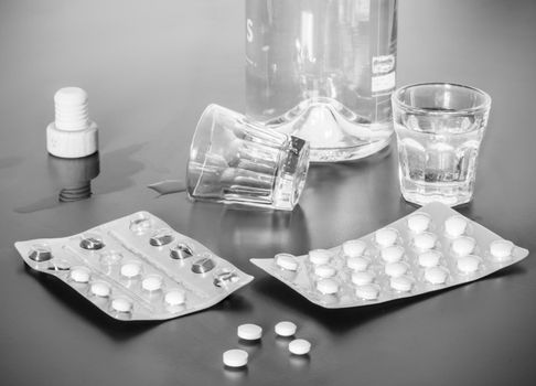 Pills and alcohol on a grey table. Concept for drug abuse.