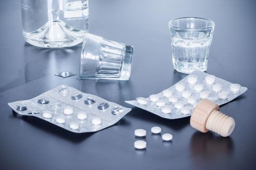 Pills and alcohol on a grey table. Concept for drug abuse.