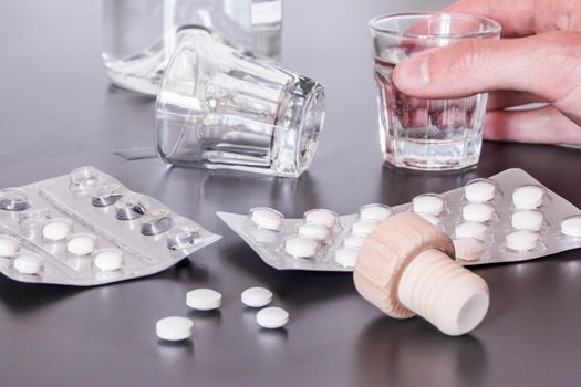 Pills and alcohol on a grey table. Concept for drug abuse.