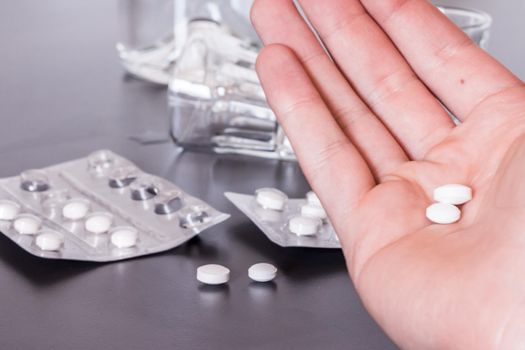 Pills and alcohol on a grey table. Concept for drug abuse.