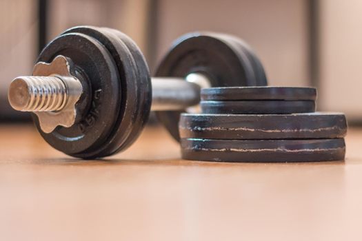 Black bar bell on the wooden floor, physical exercise