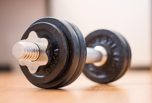Black bar bell on the wooden floor, physical exercise