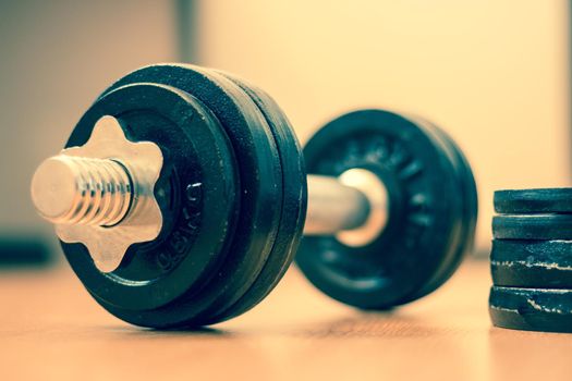 Black bar bell on the wooden floor, physical exercise