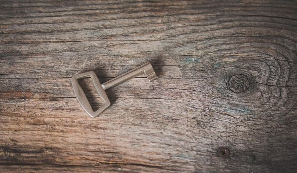 Old key is lying on a rustic wooden desk