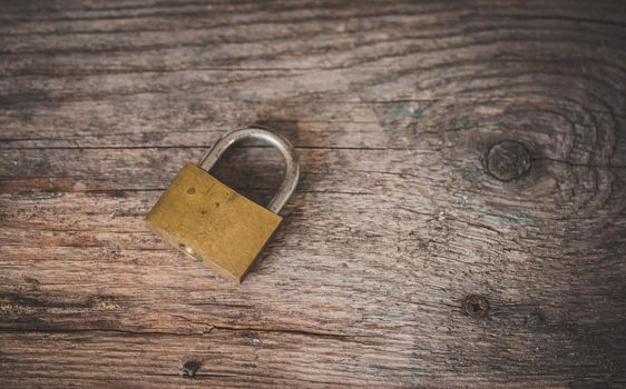 Padlock is lying on rustic wooden desk, close up